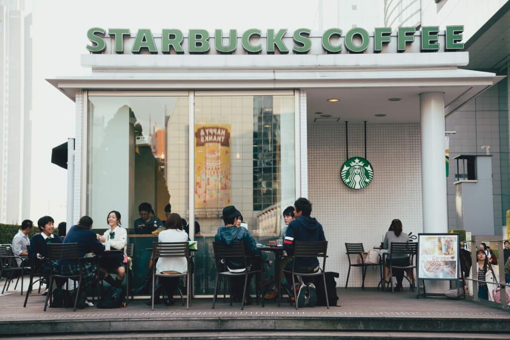 Personen sitzen vor einem Starbucks in Japan.