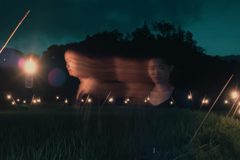 Langzeitbelichtung einer Frau bei Nacht auf Gras, geisterhafte Stimmung