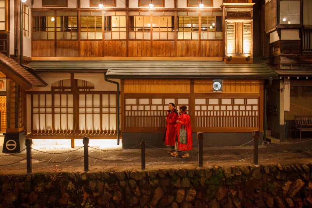 Zwei Personen spazieren am Abend in Ginzan Onsen, Japan