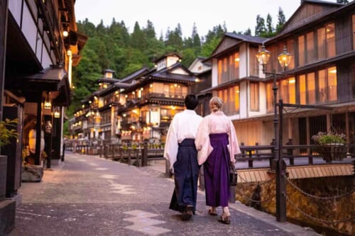 Ein Mann und eine Frau spazieren in Ginzan Onsen, Japan