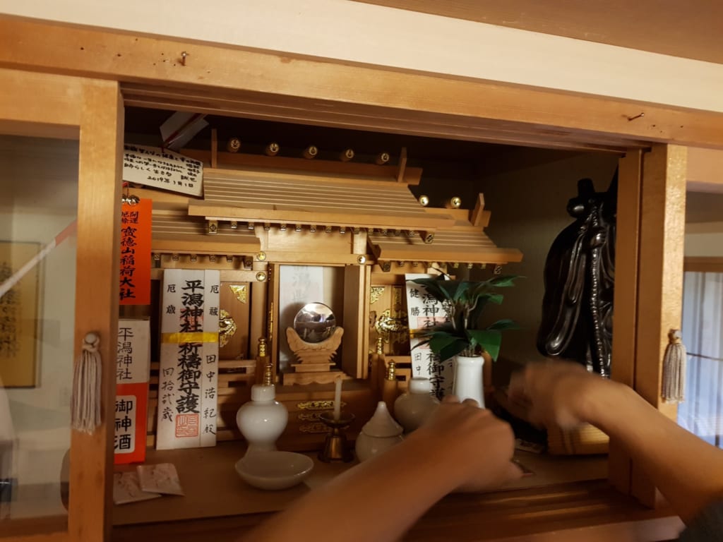Persona sistema il kamidana, l'altarino shintoista in una casa giapponese