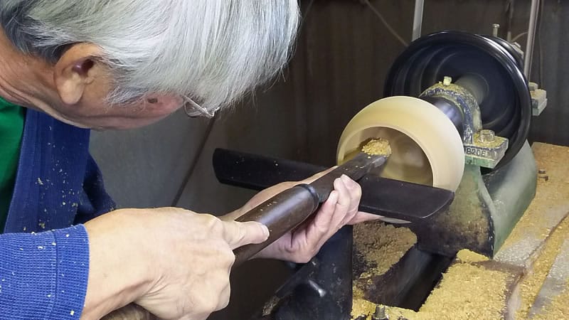 un artigiano giapponese mentre realizza una ciotola da go tradizionale