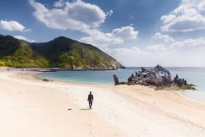 Uomo cammina da solo sulla spiaggia di Okinawa