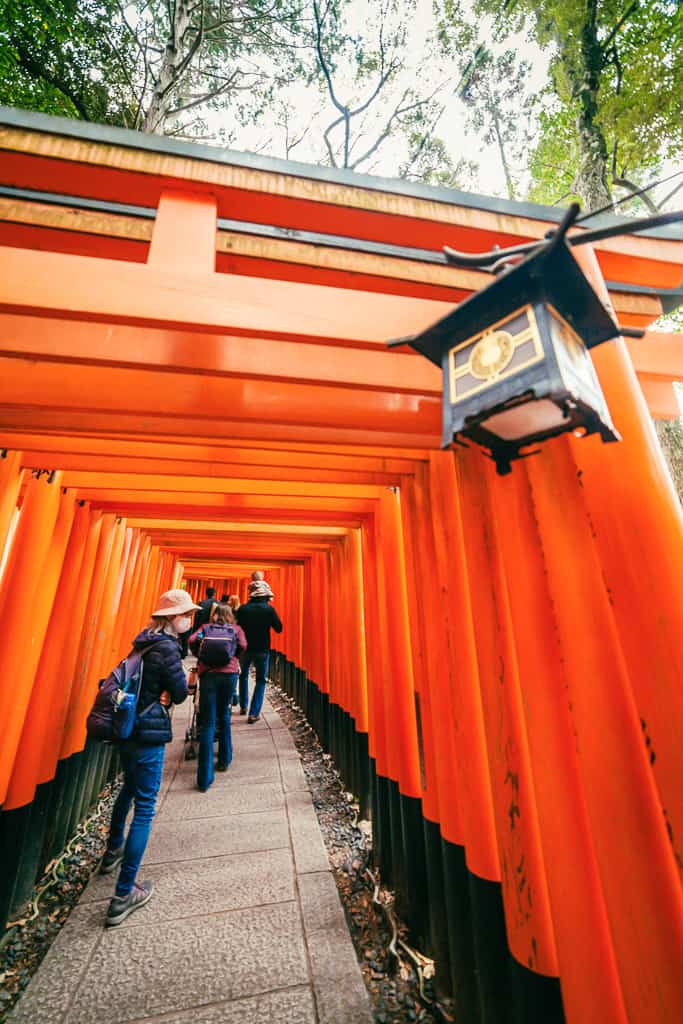 Turisti tra i torii rossi al Fushimi Inari a Kyoto